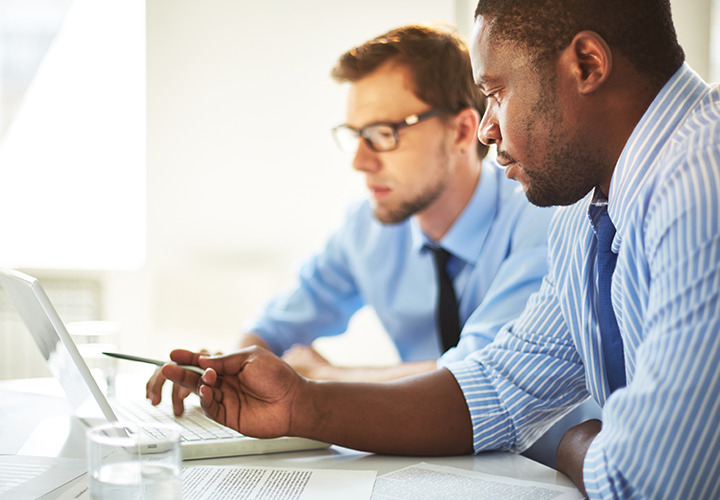 Photo of business men looking at laptop pointing with pen