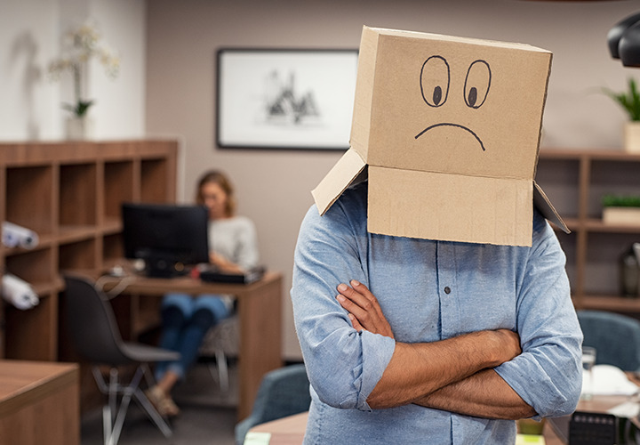 Person standing with box on head and a frowny face on it