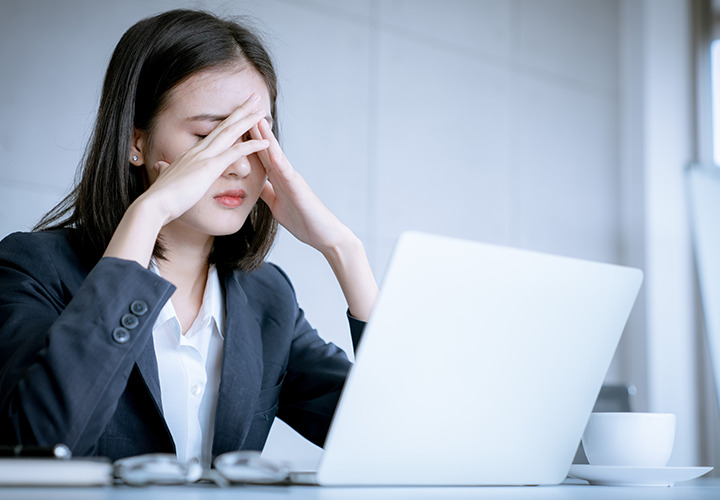 Frustrated business woman is seated at desk with laptop