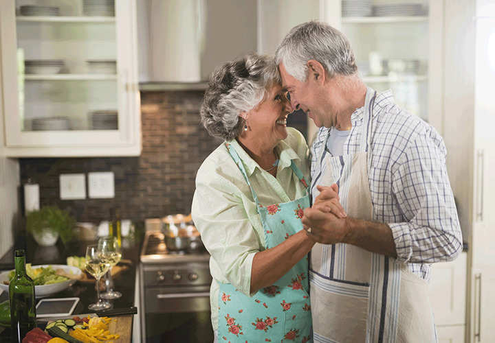 A couple are dancing in the kitchen while they prepare a meal