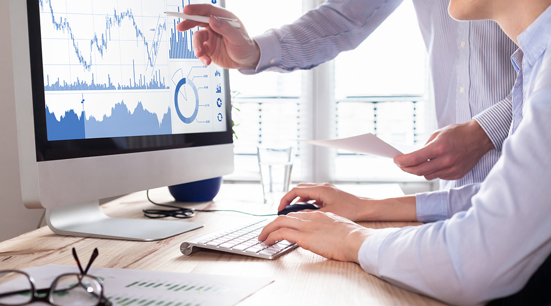 Person at a desk working on computer working on charts