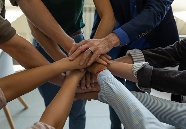 Several people have their hands on top of each over's hands