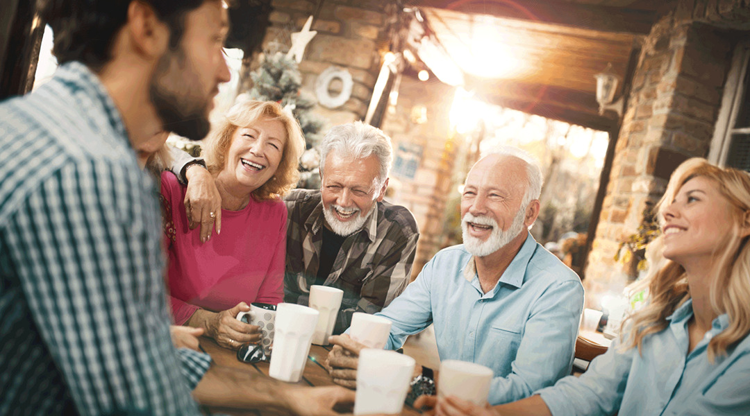 A group of people at a table with drinks smiling and laughing