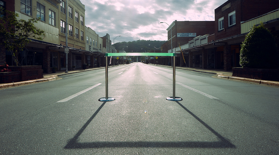 Two stanchions with a green ribbon in middle of street