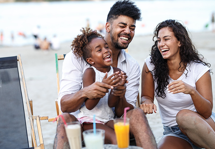 Happy family sharing a laugh in canvas chairs at the beach