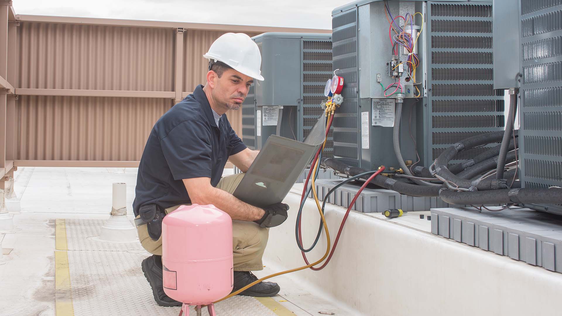 HVAC repair technician working on compressor unit checking R-22 levels