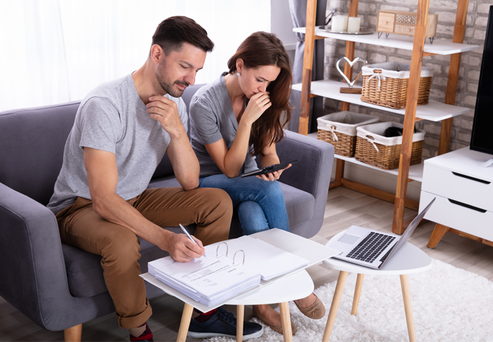 Man and woman are seated with open binder and calculator