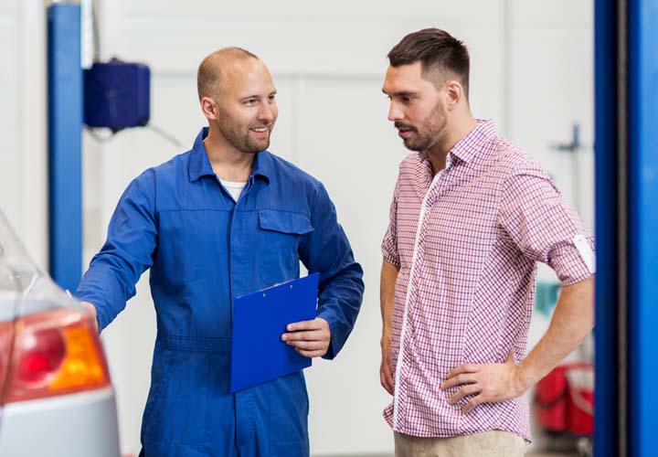 Mechainic talking to customer next to their car