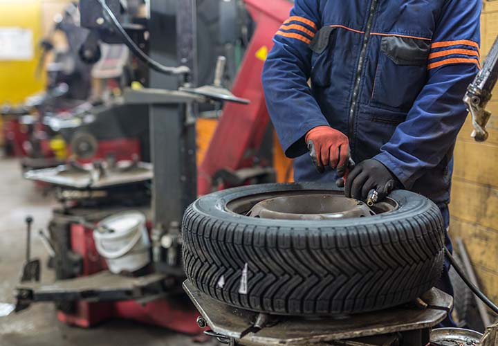 tire shop worker filling tire with air in a shop
