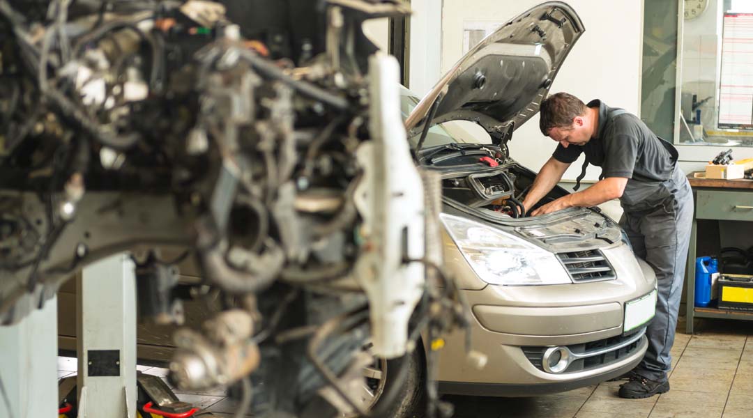 Mechanic reaching inside engine bay of vehicle