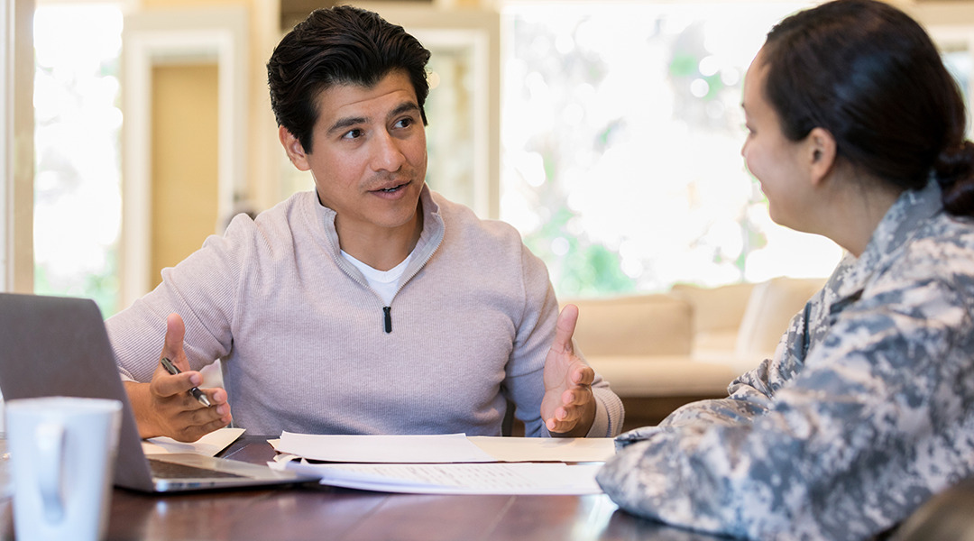 Seated man has a discussion with woman over paperwork