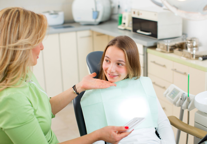 Girl laying in dentists chair talks to dentist in office
