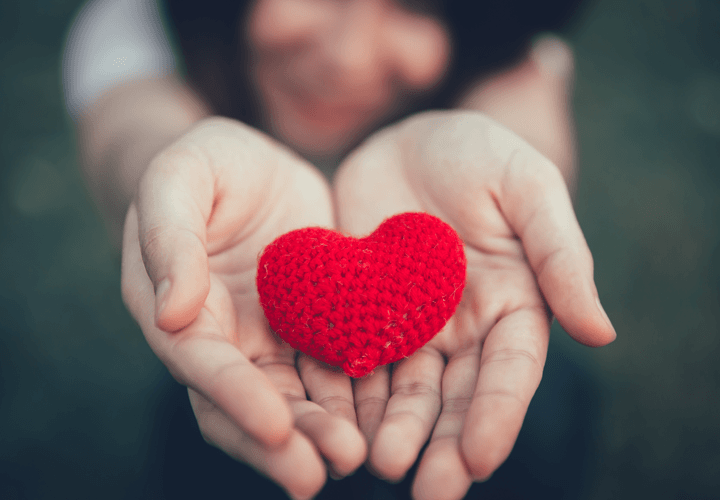 Person holding up a red knitted heart in hands
