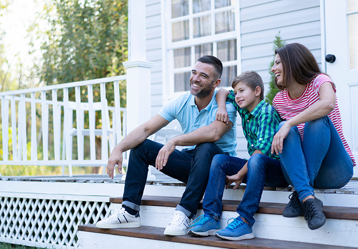 A happy family sits together on porch