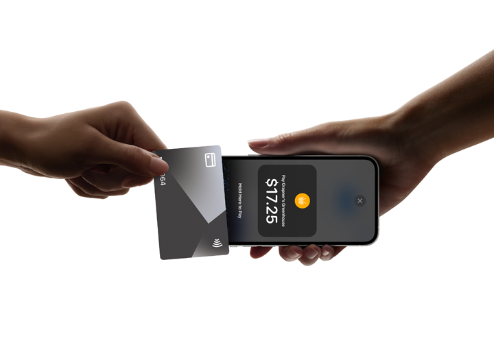 A hand is holding a contactless card to an iPhone with Tap to Pay which displays the payment amount.