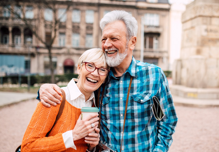 A senior couple is enjoying each other's company on a city street.