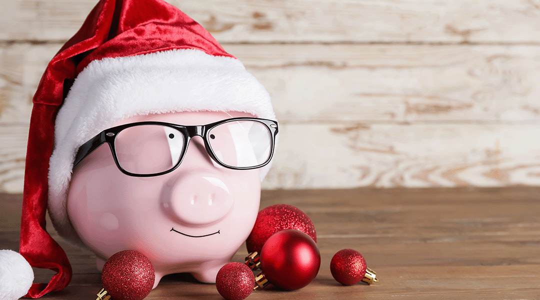 A classic pink piggy bank with glasses, Santa hat and red ornaments.