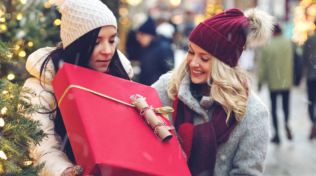 Two women holding a present on street in the daytime.
