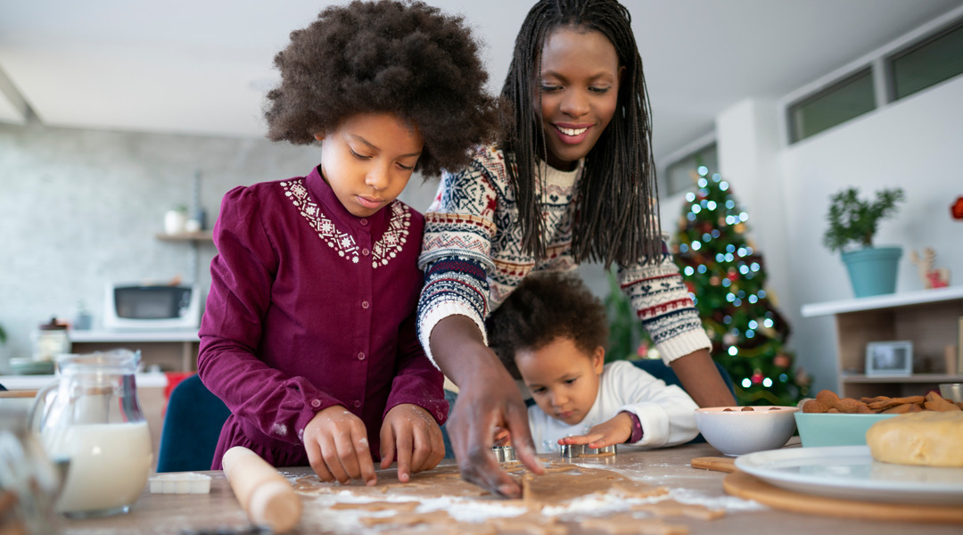 A family is making baked goods surrounded by ingredients.