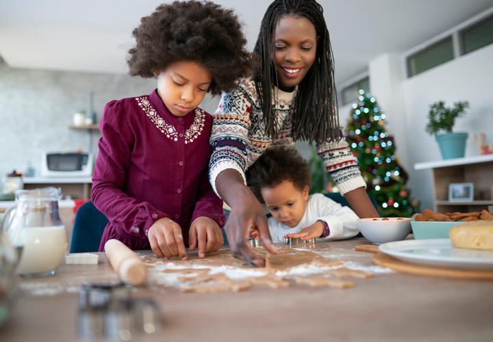 A family is making baked goods surrounded by ingredients.