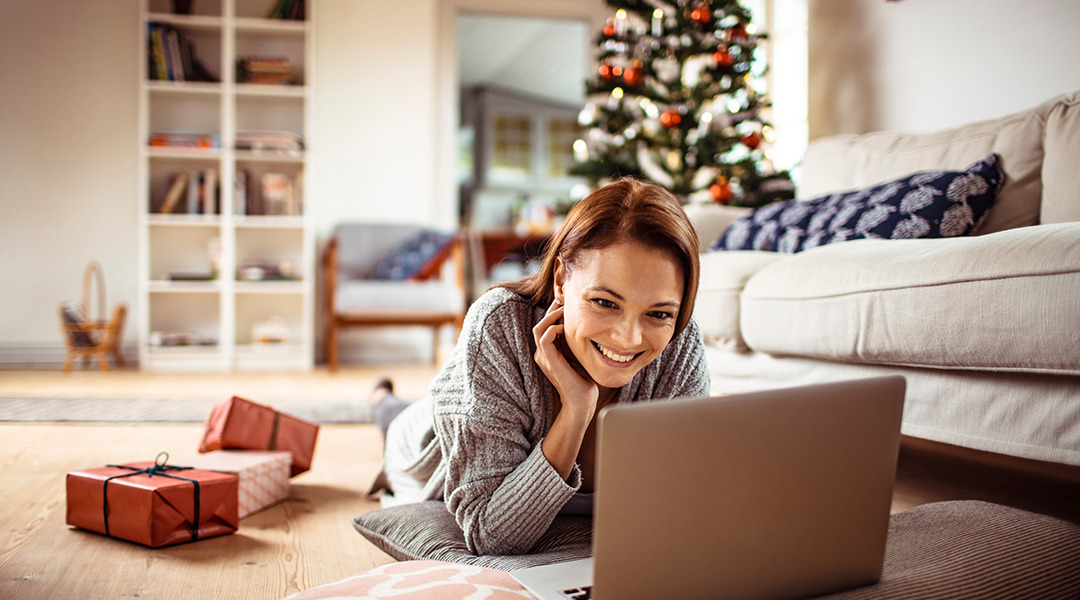 A woman is looking at laptop on floor during Christmas.