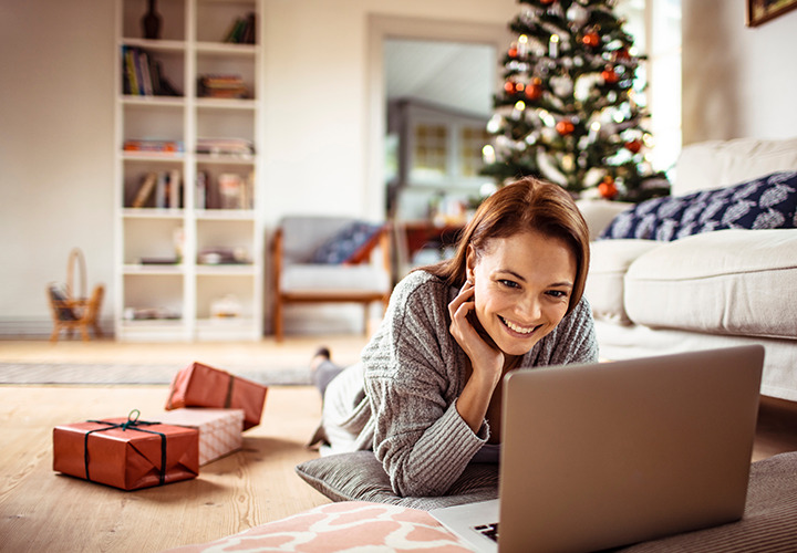 A woman is looking at laptop on floor during Christmas.