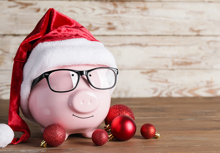A classic pink piggy bank with glasses, Santa hat and red ornaments.