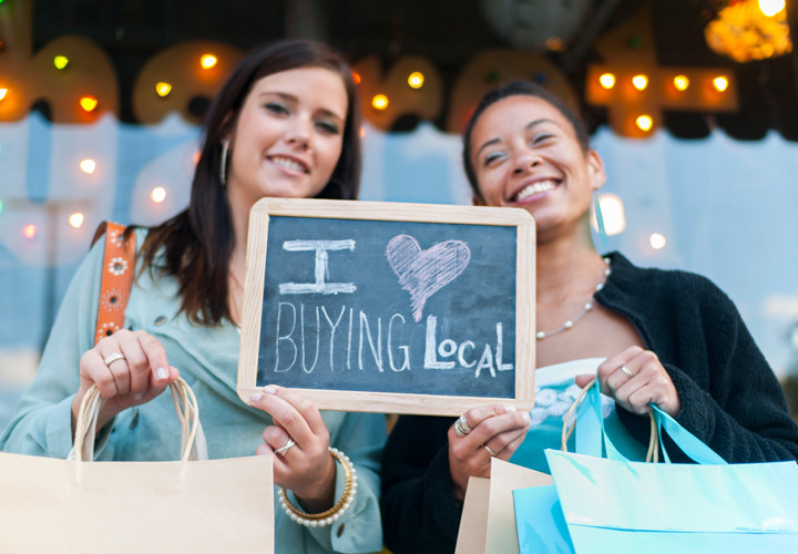 Two women hold a sign reading "I love shopping local".